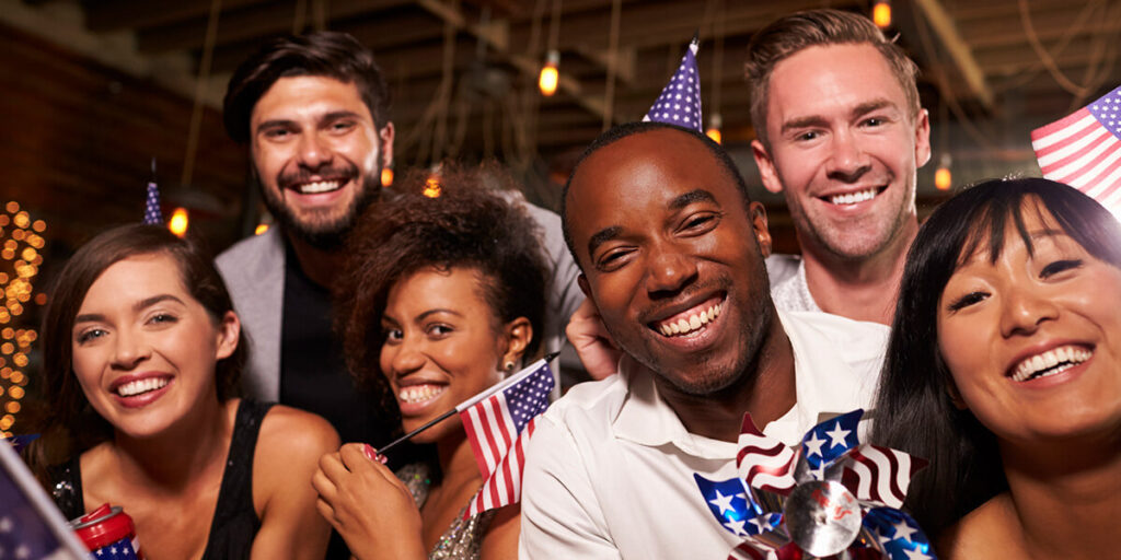 Friends gathered around each other holding Amercian flags. 