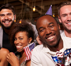 Friends gathered around each other holding Amercian flags.